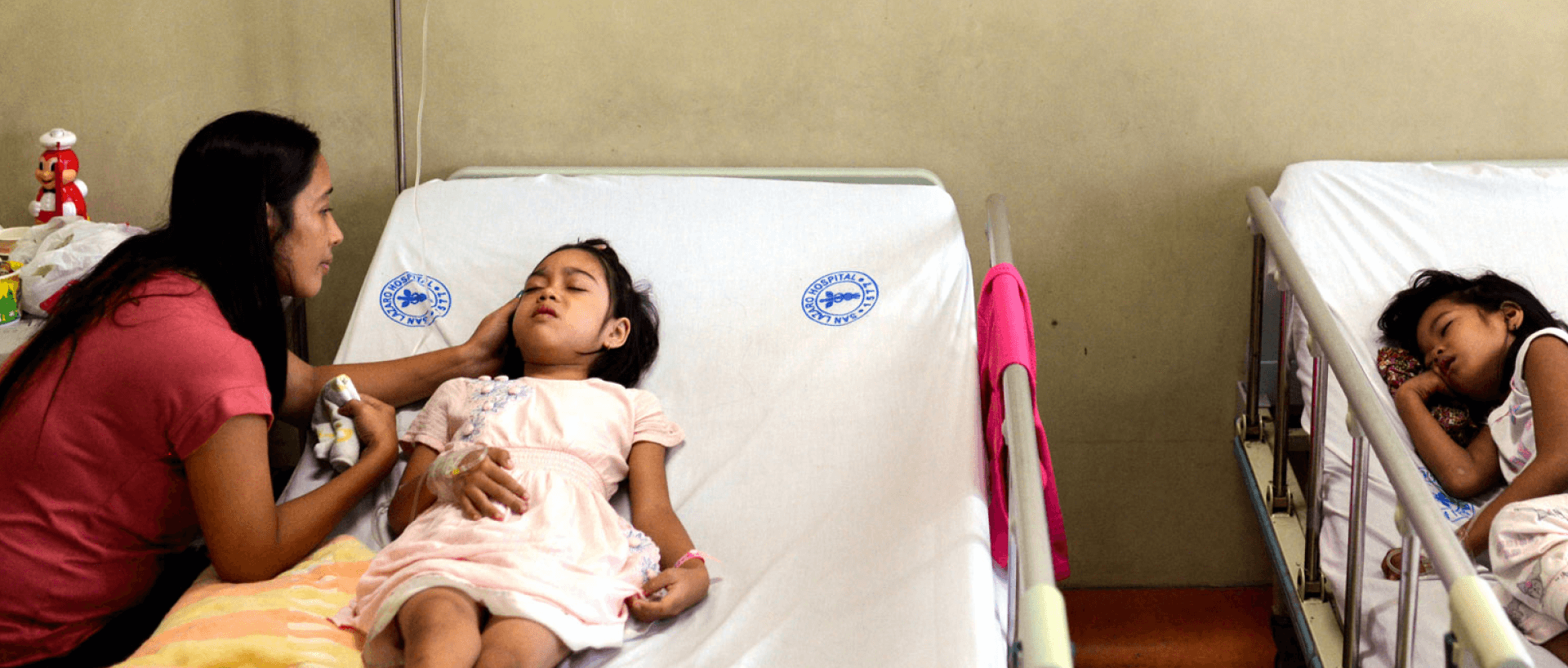 Photograph of children in hospital beds being nursed for