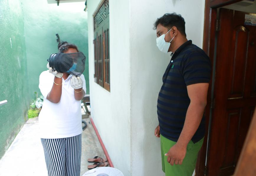 A WMP staff member explains how a mosquito trap works to Kasun Chameera