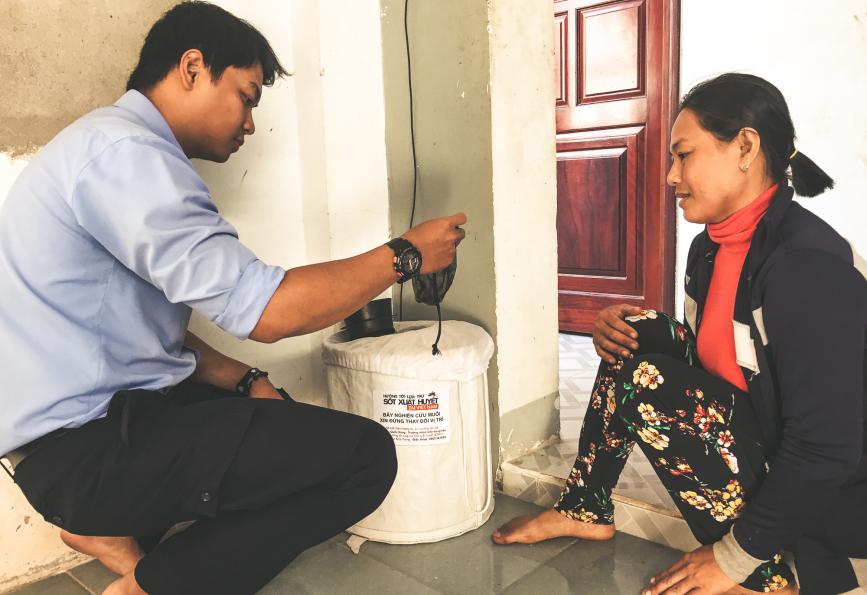 Two people examine a BG mosquito trap in Vietnam