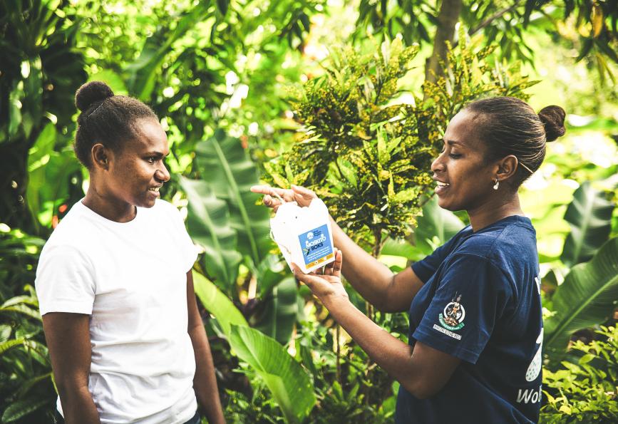 A World Mosquito Program staff member in Vanuatu shows a resident how to hang their mosquito box 